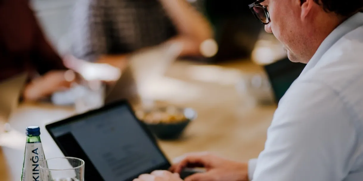 Vīrietis strādā ar planšeti pie galda birojā.