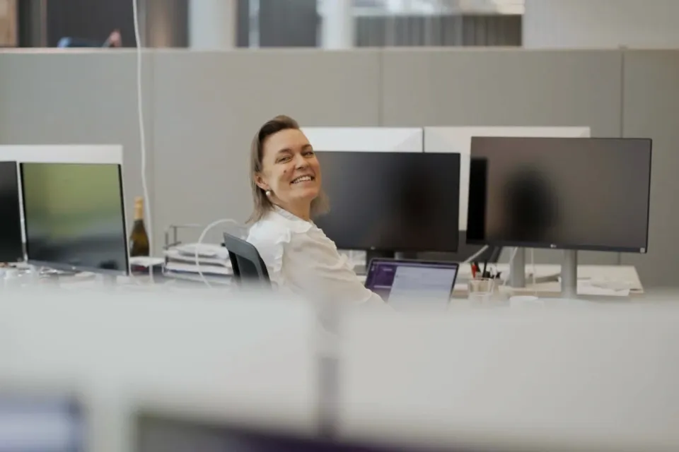 Sieviete smaida pie darba galda birojā.