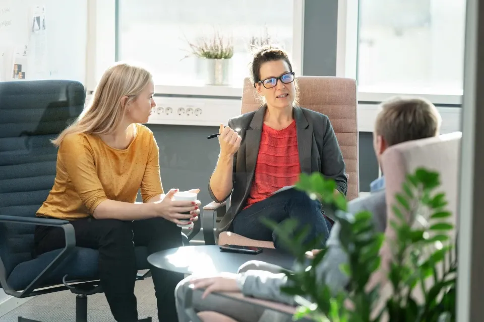 Trīs kolēģi iesaistījušies koncentrētā sarunā gaišā biroja telpā