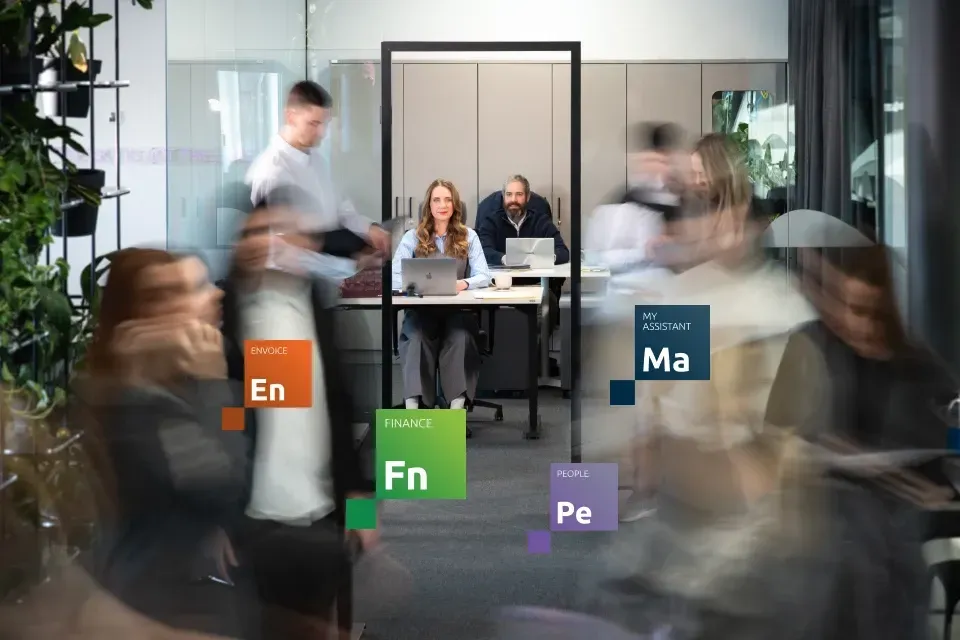 Biroja vide ar strādājošiem cilvēkiem un Jumis moduļu apzīmējumiem.