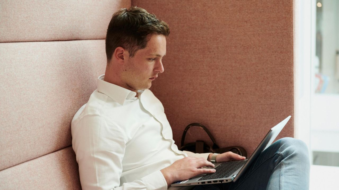 Jauns darbinieks koncentrēti strādā pie klēpjdatora ērtā un klusā darba zonā.